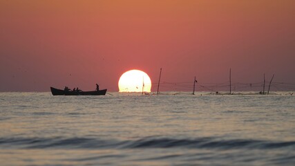 Sunrise silhouette of fishing boat on sea