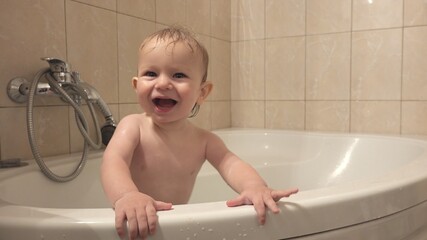Happy baby child standing in bathtub smiling and laughing, clean time