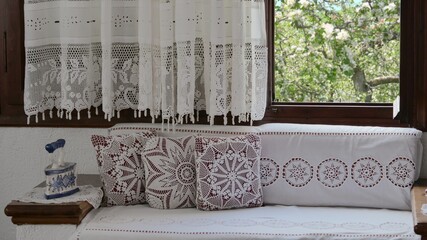 Rustic traditional embroidery curtains and divan framing the wooden window to the flowered trees of yard orchard, beautiful countryside decor