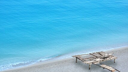 Abandoned wooden pontoon with bench on wild seaside secluded beach