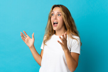 Young blonde woman isolated on blue background with surprise facial expression