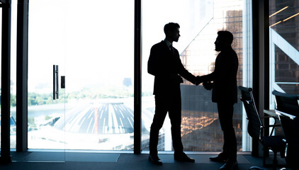 Silhouette of male employees in formal clothing doing handshake during business meeting in office enterprise for find solutions negotiations, proud ceo have cooperation brainstorming on idea