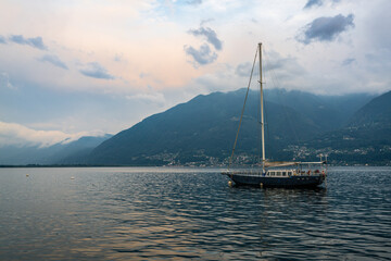 Sailing boat in middle of lake Maggiore at dusk at the border of Italy and Switzerland