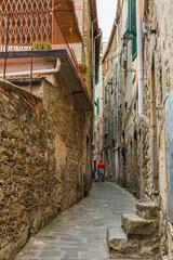 Lovely view of a quaint narrow road and houses with ancient facades on each side in the historic village Corniglia at the coastal area of Cinque Terre, Liguria, Italy.