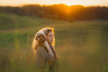 woman and two dogs on a field at sunset.