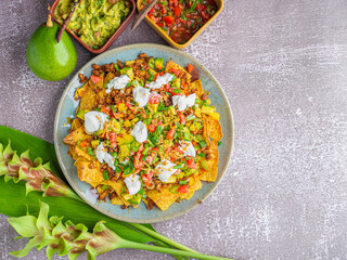 Loaded minced pork nachos with guacamole and salsa dips