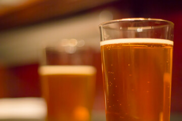 Glasses of light beer on a pub background.