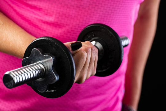Woman in pink top lifting dumbbell, close up