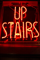 Up stairs red neon light sign on a pub in London, Uk.