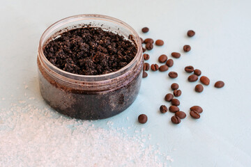 Fototapeta na wymiar Round jar full of coffee scrub with roasted beans and sea salt as homemade facial and body exfoliation treatment. Homemade cosmetics for peeling and rejuvenation, anti-cellulite spa product