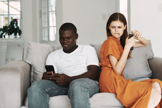 women in a sundress looking at a man with a mobile phone 