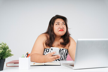 Upset bored asian chubby woman at working desk in office.