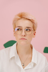 Sad young woman with short blond hair, round glasses and stars eye makeup