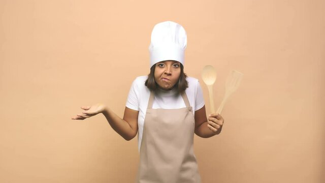 Young cook indian woman shrugs shoulders and open eyes confused