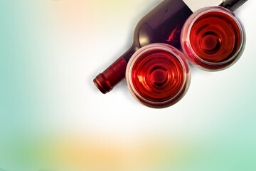 
Two glasses and a bottle of red wine on a pastel soft background.