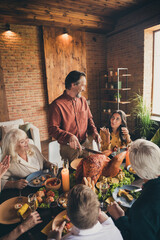 Vertical photo of full family gathering sit bristled father cut stuffed turkey communicate wife suggest better knife served dinner big table generation in evening living room indoors