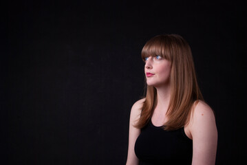 Portrait of a thoughtful woman with a black background, looking away from camera.