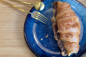 Fresh croissants with chocolate on a blue plate on wooden tray