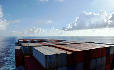 Fully loaded container ship sailing through a blue, calm ocean. View on the stack of the containers...