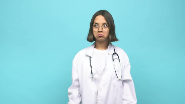 Young doctor indian woman shrugs shoulders and open eyes confused