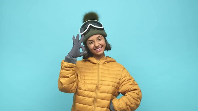 Young snowboard indian woman cheerful and confident showing ok gesture