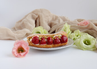 French pastry eclair with flowers, strawberry cake with cream and summer flowers on a white table, food art photography, social media photo