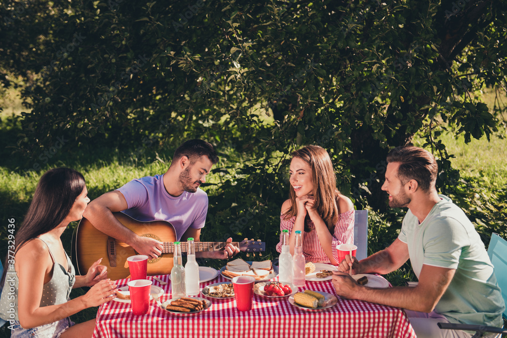 Poster Four nice attractive cheerful cheery guys group meeting singing song playing instrument hit singing song single live acoustic sound spending weekend enjoying rest chill romantic sunny day