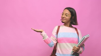 Young student indian woman showing a copy space on a palm and holding another hand on waist