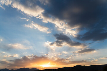 Beautiful bright sunset sky over the mountains silhouette . Dramatic orange clouds after sunset. Nature backgrounds. Golden sunset.