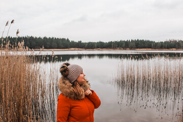 Young girl in a red jacket enjoys nature. Early winter