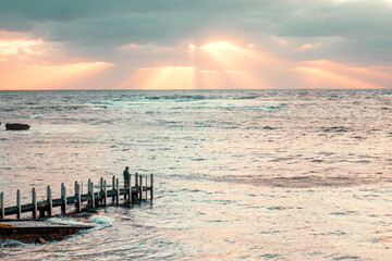 Silhouette of fishing off a wooden pier from the beach at sunset