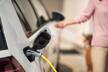 Close up of a electric car charger with female silhouette in the background
