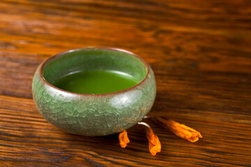 Matcha tea with dry flowers on a wooden background.