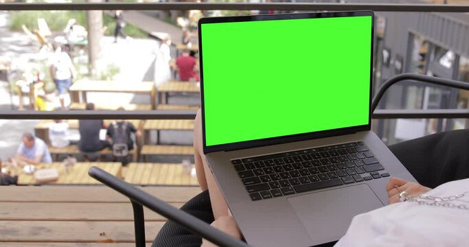 Close up Woman using MacBook Pro with keyed blank green screen in outdoor co-working park. Travel freelance business lifestyle. Internet communication chat. Typing message, searching. Chromakey mockup