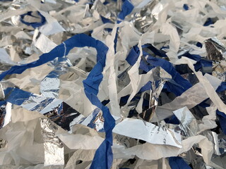 White, silver and blue paper is cut into thin ribbons. Props for a paper party