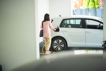 Woman charging a electric car at a garage
