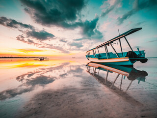 Obraz premium Indonesian fishing boat on the beach at low tide. Strong sunset colors and reflections and reflections in the water