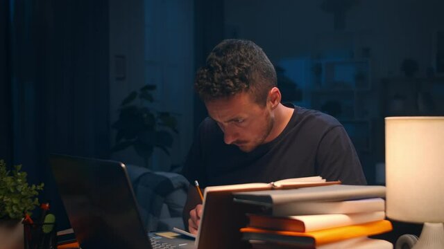 Young man working late at home in the living room and receiving a nice sms