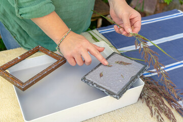 Woman holding frame for making paper sheets from waste paper pulp. Selective focus. Decorative and applied art. Recycling concept, ecology.