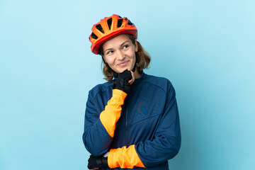 Young cyclist woman isolated on blue background and looking up