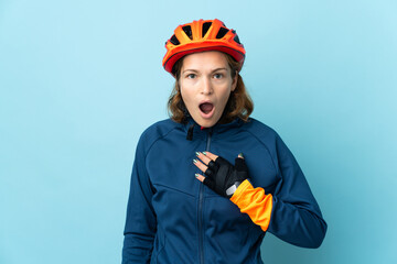 Young cyclist woman isolated on blue background surprised and shocked while looking right