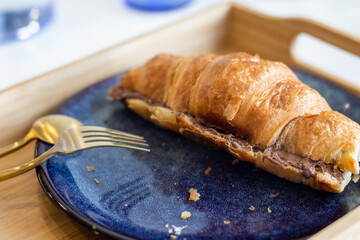 Fresh croissants with chocolate on a blue plate on wooden tray