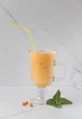 Glass cup with fresh melon and sea buckthorn smoothi on a light background.