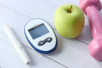 Close up of diabetic measurement tools, apple and dumbbell on table 