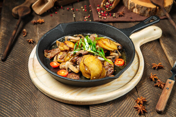 Roasted potatoes and beef meat in cast iron pan