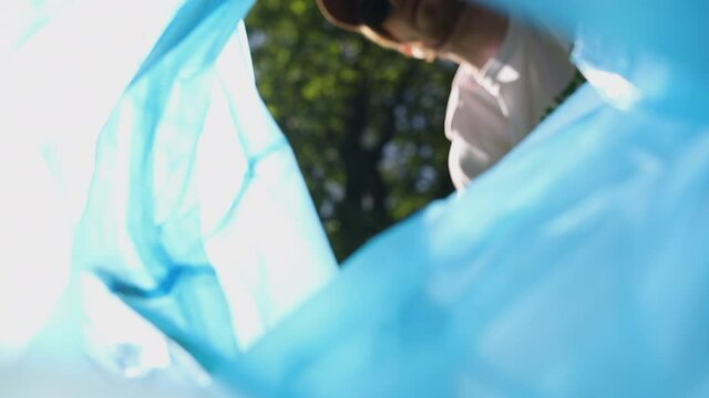 POV camera inside of trash bag, man volunteer throwing litter Spbi. person ecology activist. plastic bottle in a waste bag. view from bag. Garbage collection in the forest.