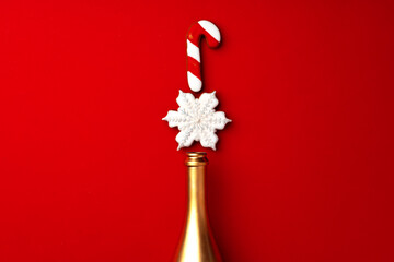 Gold champagne bottle with gingerbread cookies on red background