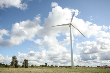 Wind turbine in a sunny day with blue sky and clouds. Wind farm eco field. Green ecological power energy generation. 