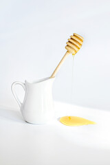 Honey flowing from turfed honey stick. honeys do on white background. Breakfast cream jug