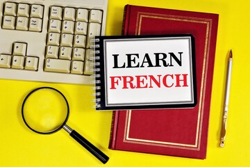 Learn French.- writing text in a notebook on a textbook. Learning spelling grammar and...